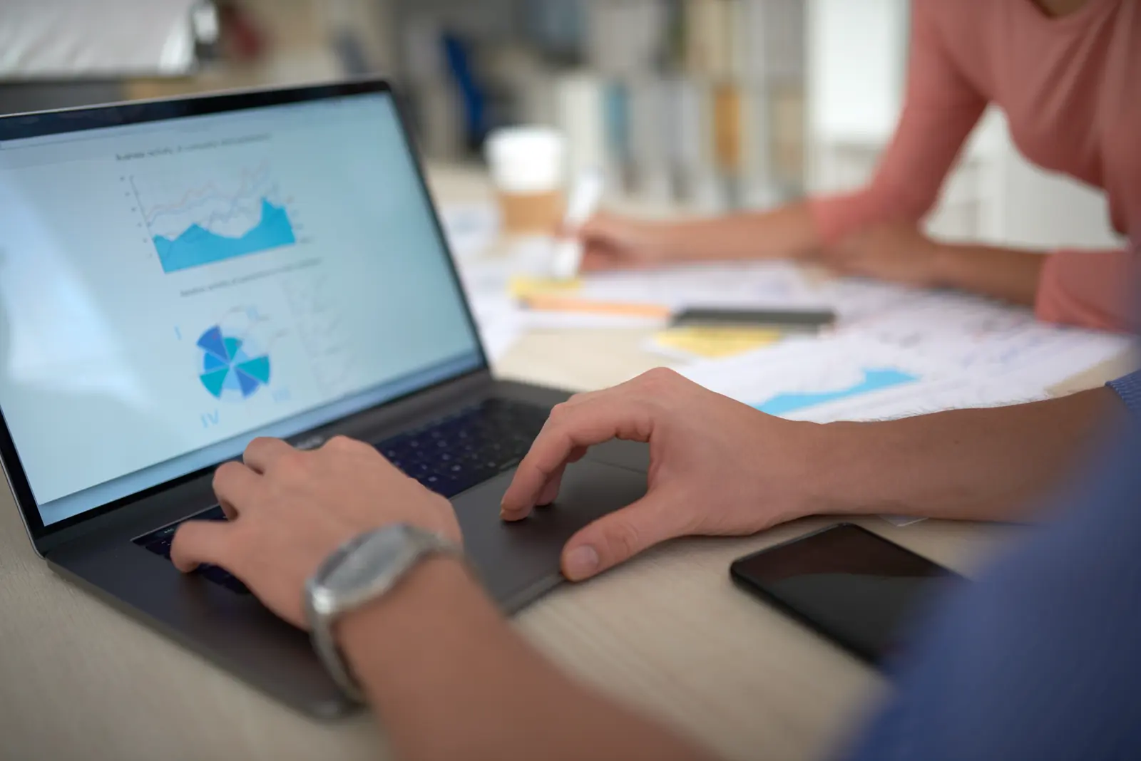 Laptop mit Diagrammen und Kennzahlen, Hände auf der Tastatur